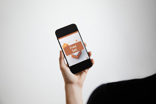 A hand holding a black smartphone against a light gray background. The phone screen displays a promotional graphic with the words 'Free Set' in white text on an orange label.