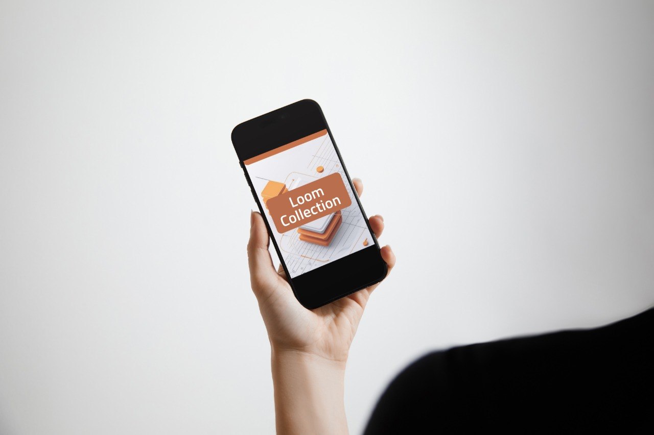A hand holds a black smartphone displaying an app screen titled 'Loom Collection' against a clean light gray background.